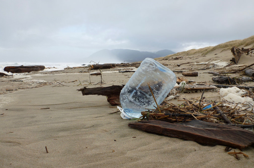 Plastic drinking water storage jug tossed up on the sand by the last high tide