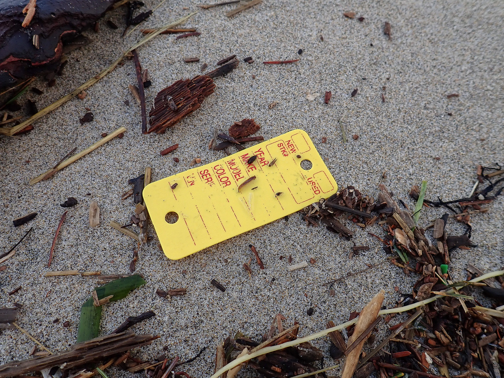 A yellow tag, looks like a tag for a key ring from an auto repair shop- New, used, make, model, color...