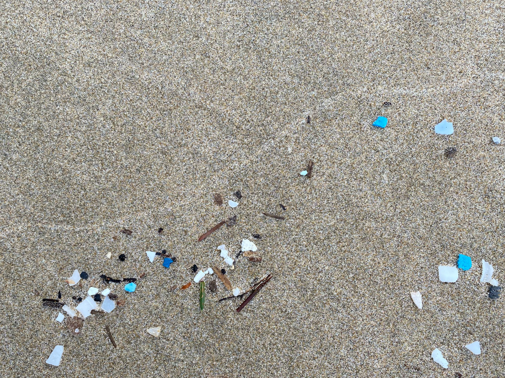 Bunch of drifted blue and white plastic fragments left on the sand