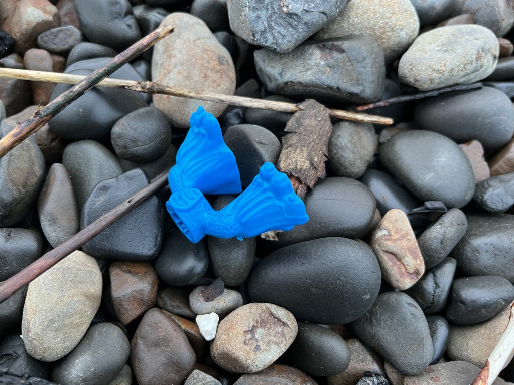 A piece of a plastic character resting on cobbles