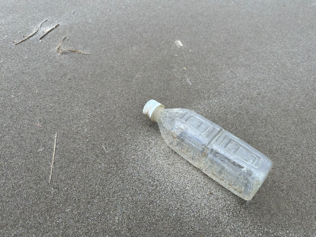 Empty plastic bottle resting on the sand.