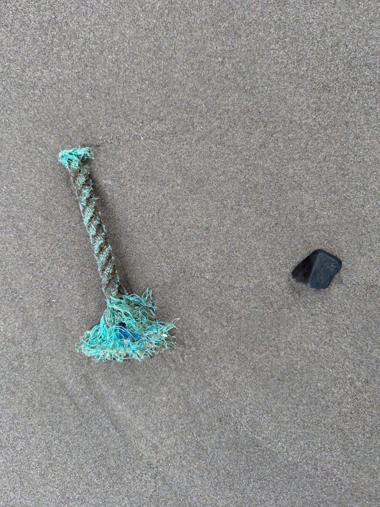 A small length of commercial line and a pebble rest on the sand.
