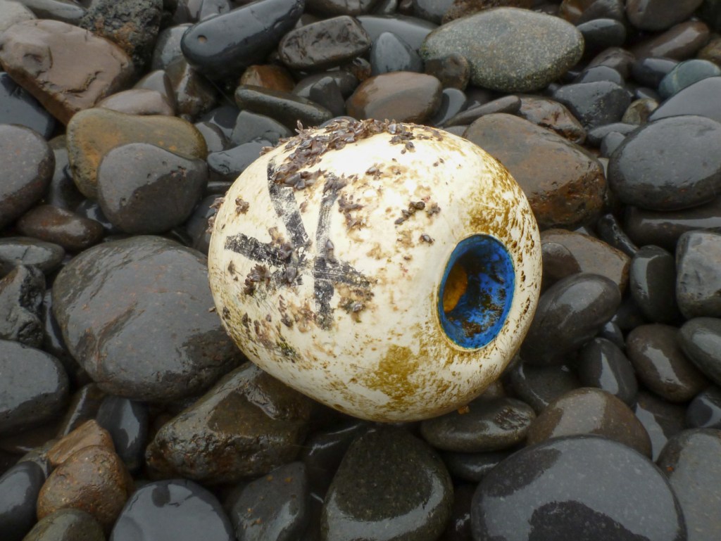 Closeup of a styrofoam float with Chinese characters resting on the cobbles.