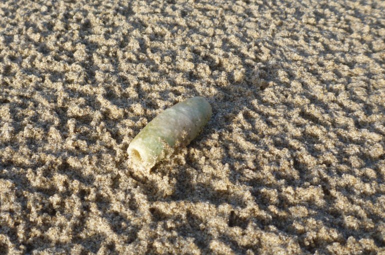 A plastic spacer rests on rain-dimpled sand.