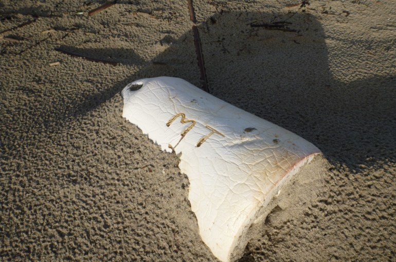 Lost marker buoy partially buried in the sand.