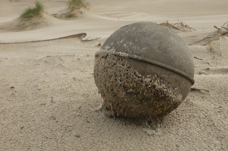 A lost buoy rests on the sand.