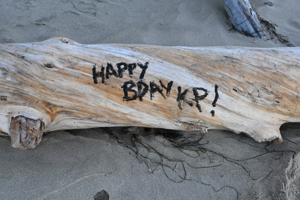 A piece of driftwood adorned with a birthday message HAPPY BDAY KP!