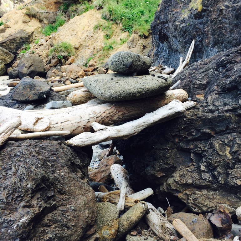 Someone has placed driftwood and cobbles over a gap between two rocks.