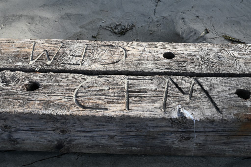 Heavy timbers with the initials CFM notched into them rest on the sand.