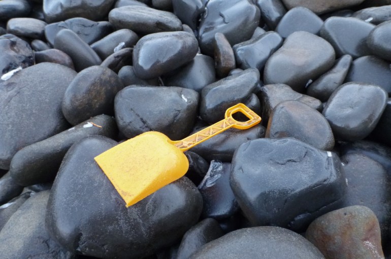 A small plastic sand shovel rests on the cobbles.