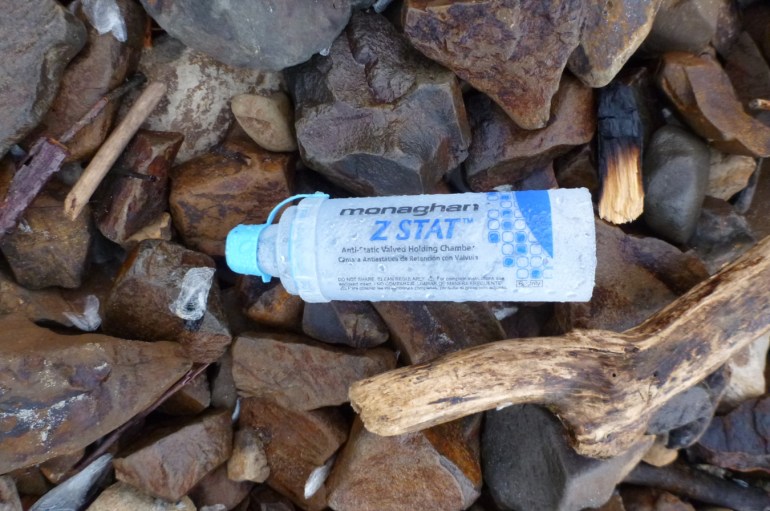 A discarded holding chamber for an asthma inhaler rests on the cobbles.