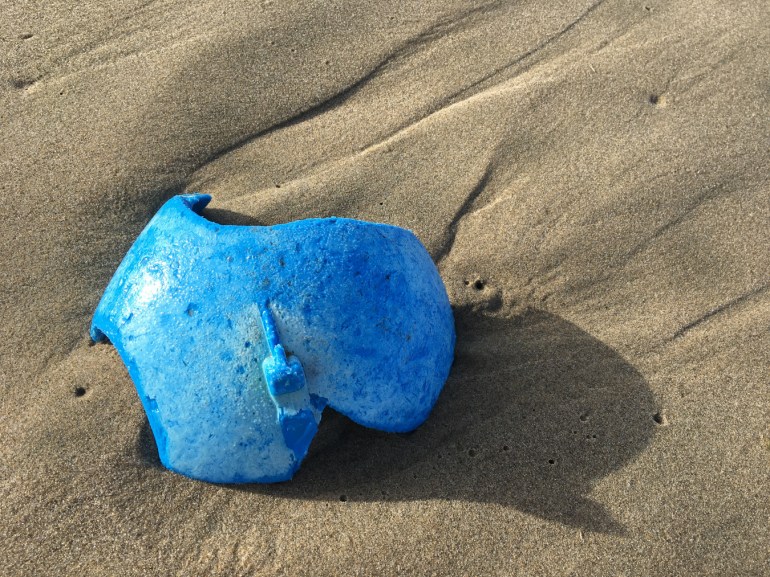 A fragment of a beautiful blue buoy rests on the sand.