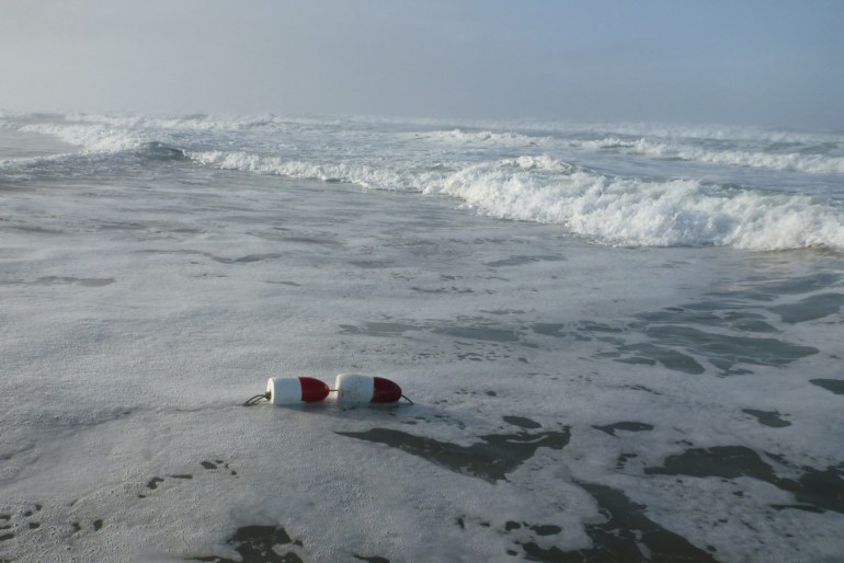 Red and white floats identify lost crab gear drifted into the surf zone.