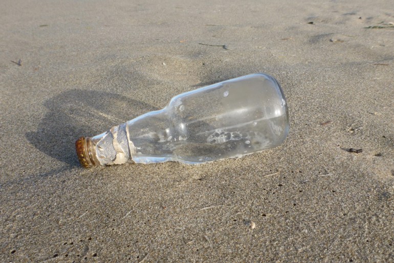 An empty and drifted bottle rests on the sand.